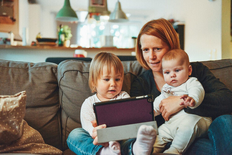 Mutter mit Kindern schaut auf das Tablet